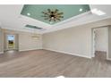 Bright dining room with tray ceiling, wood-look floors, and access to the kitchen at 144 Spring Dr, Rotonda West, FL 33947