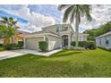 Inviting home exterior with a lush green lawn, mature landscaping, and an arched entryway at 1671 Mellon Way, Sarasota, FL 34232