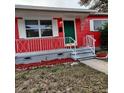 Close-up of a quaint front porch with red exterior, white railing, and a green front door at 1711 41St S St, St Petersburg, FL 33711