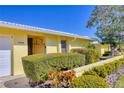 Front entrance of a yellow house with white garage door and neat landscaping at 3749 Amesbury Ln # 5608, Sarasota, FL 34232