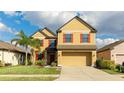 Two-story home with tan siding, red shutters, a well-manicured lawn and a 2 car garage at 14318 Fissore Blvd, Wimauma, FL 33598