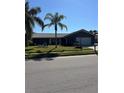 Well-maintained front yard with green lawn and tropical palm trees for a serene setting at 2930 Tuckerstown Dr, Sarasota, FL 34231