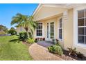 Exterior home entrance with a brick path, mature palm tree, and lush landscaping at 4244 Reflections Pkwy, Sarasota, FL 34233