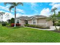 Charming single Gathering home featuring a lush lawn and mature landscaping including palm trees and flowering shrubs at 5276 Mahogany Run Ave, Sarasota, FL 34241