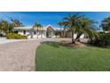 Charming single-story home featuring brick driveway, lush lawn, and mature palm trees at 627 Dundee Ln, Holmes Beach, FL 34217