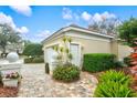 Close up of the garage, featuring manicured landscaping, and custom paver driveway at 7327 Kensington Ct, University Park, FL 34201