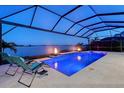 Expansive pool and patio area with fire pit and lake view at night at 8063 Waterbend Trl, Sarasota, FL 34240