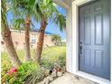 Gray front door entrance with landscaping and palm trees at 9918 50Th Street E Cir, Parrish, FL 34219