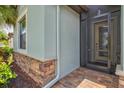 Close-up of the entrance featuring stone accents, a screened front door, and brick pavers at 12675 Richezza Dr, Venice, FL 34293