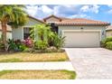 Inviting single-Gathering home with lush tropical landscaping, a clay tile roof, and a two-car garage at 12675 Richezza Dr, Venice, FL 34293