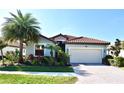 Beautiful single-story home featuring a barrel tile roof, tropical landscaping, and a two-car garage at 12675 Richezza Dr, Venice, FL 34293