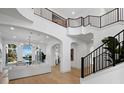 Bright foyer featuring a grand staircase, modern railings, and a view of the living area at 500 Harbor Point Rd, Longboat Key, FL 34228