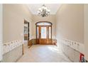 Elegant foyer features a decorative wood door, a chandelier, and tile flooring at 951 Contento St., Siesta Key, FL 34242