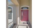 Covered entryway featuring a vibrant red front door with sidelight and transom window, with neutral stucco and white trim at 10726 Old Grove Cir, Bradenton, FL 34212