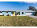 Single-story home showcasing a vibrant blue exterior with a welcoming yellow door and attached two-car garage at 114 Francis Ne Dr, Port Charlotte, FL 33952