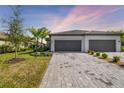 Two-car garage home with gray exterior and paver driveway at 5429 Mystic Water Cv, Bradenton, FL 34211