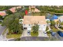 Aerial view of townhome with beige exterior, brown roof, driveway, and mature trees at 7603 Sweetbay Cir # 5-101, Bradenton, FL 34203