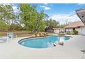 Private backyard featuring a kidney-shaped pool with a waterfall feature, a deck, and lush landscaping at 265 Beaver Ct, Venice, FL 34292