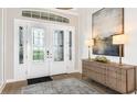 Elegant foyer featuring a stylish console table, artwork, and decorative glass front doors at 26896 Victoria Pl, Punta Gorda, FL 33955