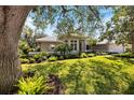 Beautiful home with lush landscaping, mature trees, and well-manicured lawn at 8579 Woodbriar Dr, Sarasota, FL 34238