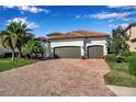 Beautiful home featuring a two-car garage, barrel tile roof and a brick paved drive framed by manicured landscaping at 13303 Swiftwater Way, Lakewood Ranch, FL 34211