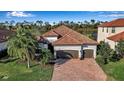 Beautiful home featuring a two-car garage, barrel tile roof and a brick paved drive framed by lush landscaping at 13303 Swiftwater Way, Lakewood Ranch, FL 34211