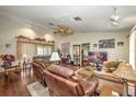 Spacious living room featuring hardwood floors, a ceiling fan, and multiple seating areas at 19484 Midway Blvd, Port Charlotte, FL 33948