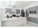 Modern kitchen with gray cabinets, a white countertop island, pendant lighting, and stainless-steel appliances at 23117 Hammond Ave, Port Charlotte, FL 33954