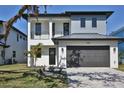 This modern two-story home features a gray garage door and a minimalist landscaped front yard with a palm tree at 2345 Oak Ter, Sarasota, FL 34231