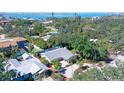 Aerial view of a home with lush trees, showcasing its proximity to water, tennis court, and a pool at 3530 Flores Ave, Sarasota, FL 34239