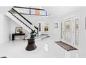 Bright foyer featuring a modern staircase, glass table with flower arrangement, and decorative front door at 55 Tidy Island Blvd, Bradenton, FL 34210