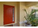 Welcoming red front door with sidelight, potted plant and textured wall at 6540 Tailfeather Way, Bradenton, FL 34203