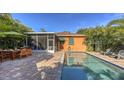 The pool is surrounded by a brick patio and lush landscaping for outdoor dining and lounging at 2047 Roselawn St, Sarasota, FL 34231