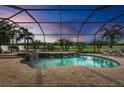 Screened pool overlooking golf course views with waterfall feature and lounge chairs at 5529 Mulligan Way, Bradenton, FL 34211