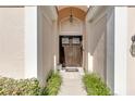 View of the home's arched front entryway with double doors and manicured landscaping at 8717 54Th E Ave, Bradenton, FL 34211