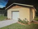 Detached garage with a white door, surrounded by lush green grass and colorful rose bushes at 3060 Arrowhead Rd, Venice, FL 34293