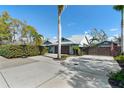 A well-manicured home exterior featuring a circular driveway, beautiful palm trees and a basketball hoop at 3951 Palau Dr, Sarasota, FL 34241