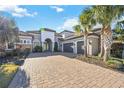 Home's exterior boasts a stone facade and a brick driveway, complemented by tall palm trees at 4744 Benito Ct, Lakewood Ranch, FL 34211