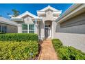 Charming front entry with brick walkway, lush landscaping, and a cozy seating area at 538 Fallbrook Dr, Venice, FL 34292