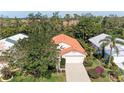 Aerial of home showcasing mature trees, red tile roof, manicured yard, and attached two-car garage at 5513 83Rd E Ter, Sarasota, FL 34243