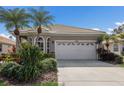 Home featuring a two-car garage with a well-maintained driveway and tropical landscaping at 7608 Teal Trce, Bradenton, FL 34203