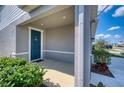 Covered front porch featuring a teal door, neutral paint and manicured bushes at 10811 High Noon Trl, Parrish, FL 34219