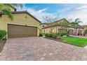 A villa with a brick driveway, attached two-car garage, and landscaped garden at 12510 Ghiberti Cir # 102, Venice, FL 34293