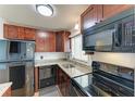 Cozy kitchen featuring granite counters, wood cabinets, and modern black appliances at 1517 Pleasant Rd # A22, Bradenton, FL 34207