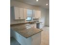 Bright kitchen featuring granite countertops, white cabinets, and a stainless steel dishwasher at 19715 Tortuga Cay Dr, Venice, FL 34293