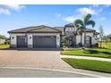 Beautiful single-story home featuring a three-car garage, tiled roof, and an attractive brick driveway with tropical landscaping at 20078 Elegante Ct, Venice, FL 34293