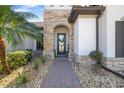 Attractive front door with stone surround and brick paver pathway, complimented by lush landscaping at 20078 Elegante Ct, Venice, FL 34293