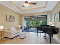 Elegant living room features a tray ceiling, tiled floor, a comfortable sofa and access to outdoor patio with lush views at 20909 Loggia Ct, Venice, FL 34293