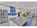 Modern kitchen with stainless steel appliances, sleek white cabinets, a large island, and vibrant blue backsplash at 3301 River Woods Dr, Parrish, FL 34219