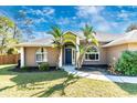 Charming single-story home with a well-manicured lawn and a blue front door with tropical plants at 4540 Maverick St, North Port, FL 34288